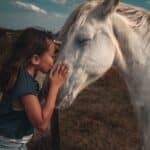 Petite fille faisant un bisous à un cheval blanc